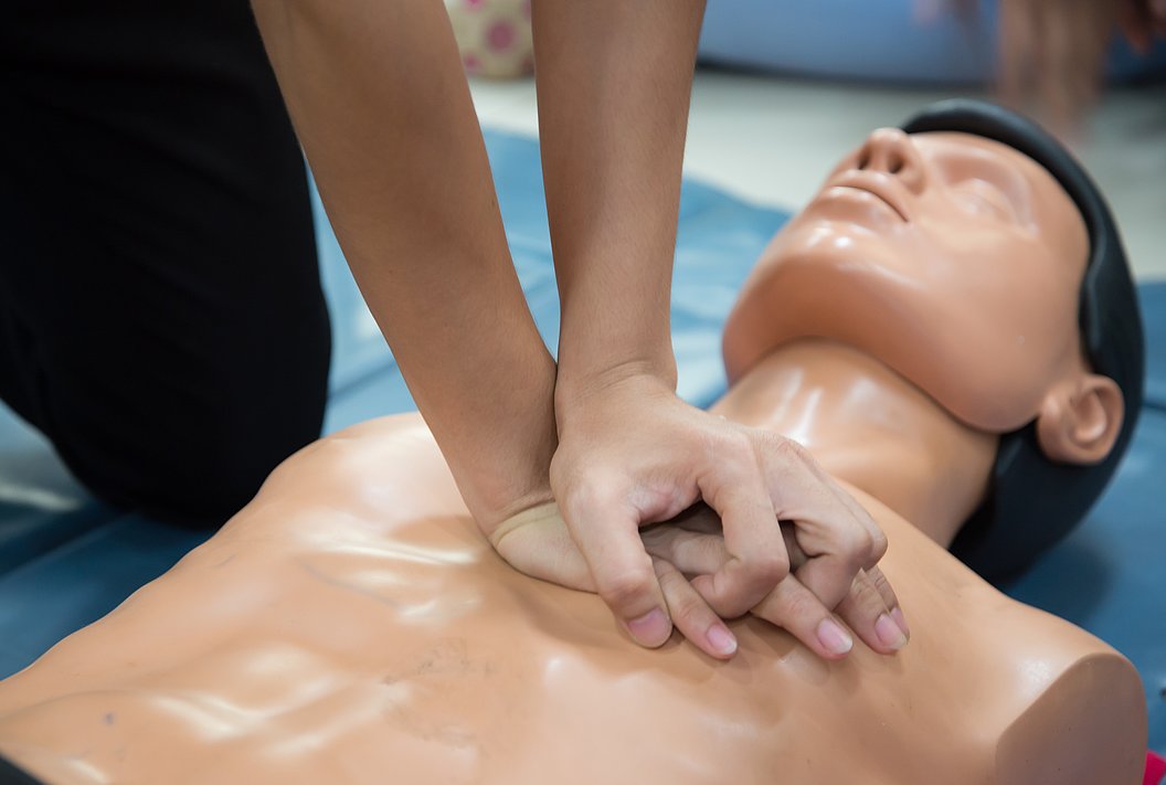 Person übt Herzdruckmassage an einer Übungspuppe aus