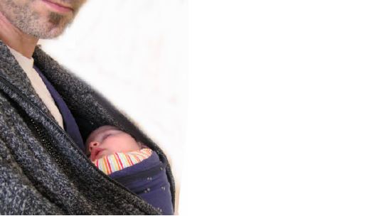 Mann trägt schlafendes Baby in Tragetuch nah am Körper